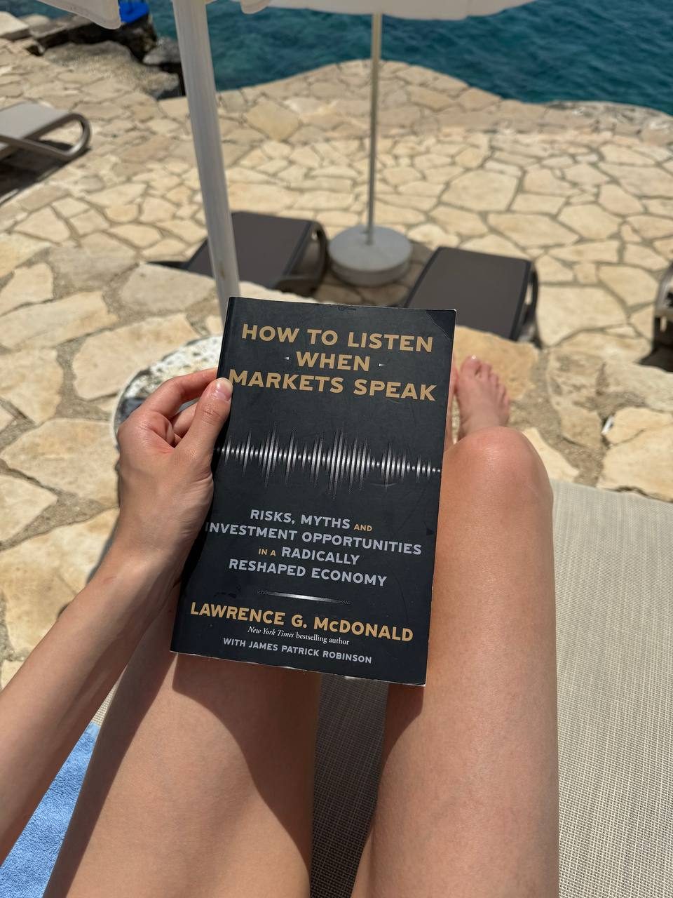 Reading How to Listen When Markets Speak under a beach umbrella